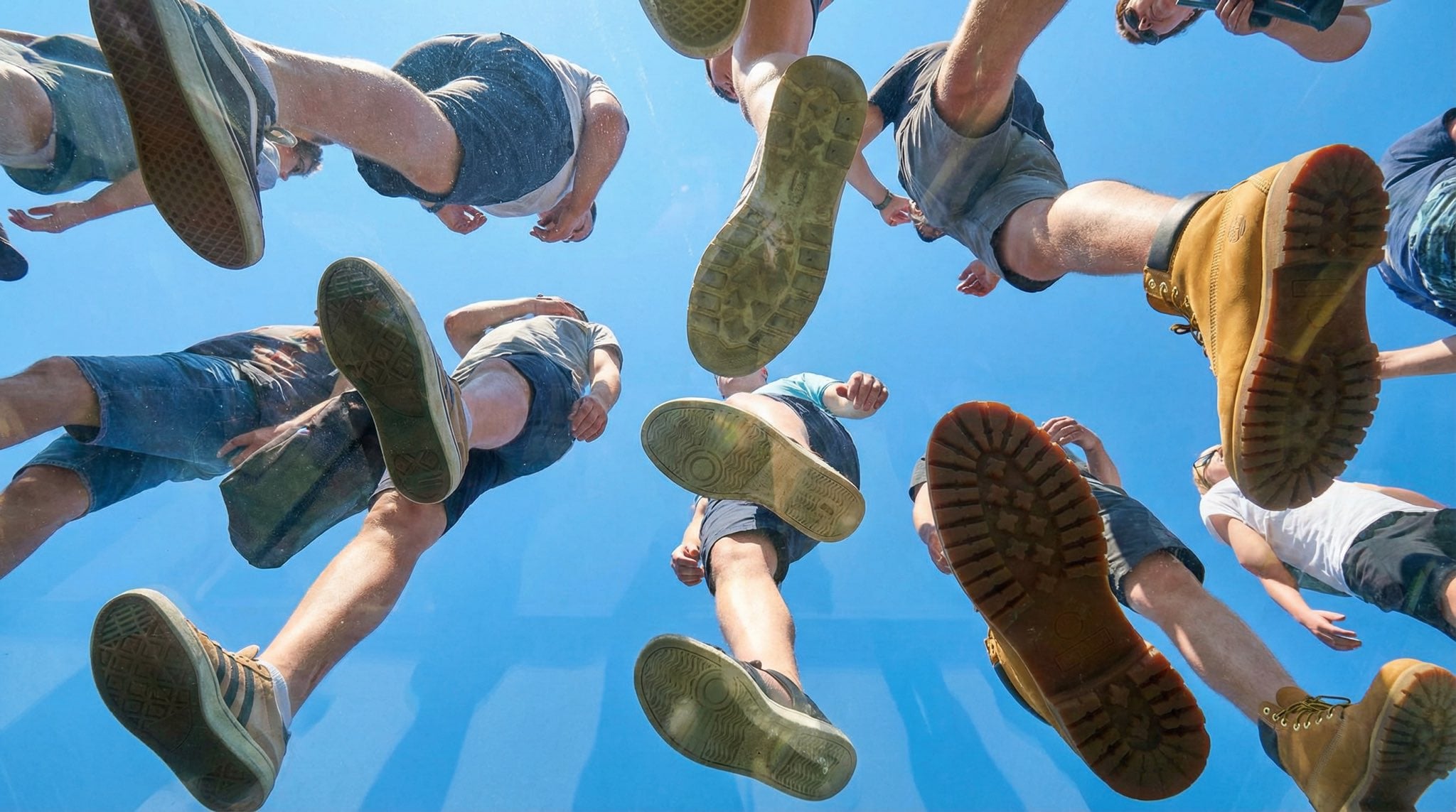 People Walking On Transparent Plexiglass Looking Up