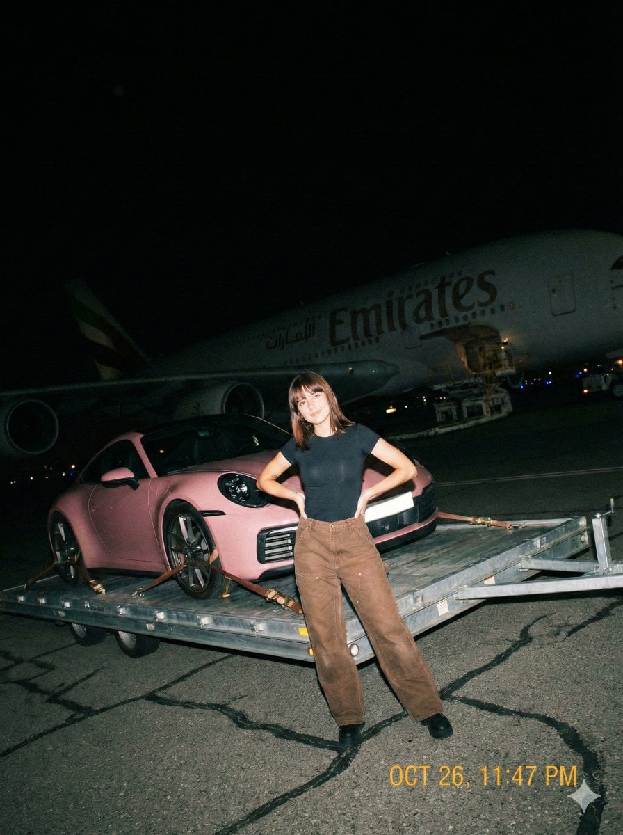 Immagine generata da IA di Donna con Porsche 911 sulla pista aeroportuale di notte con flash